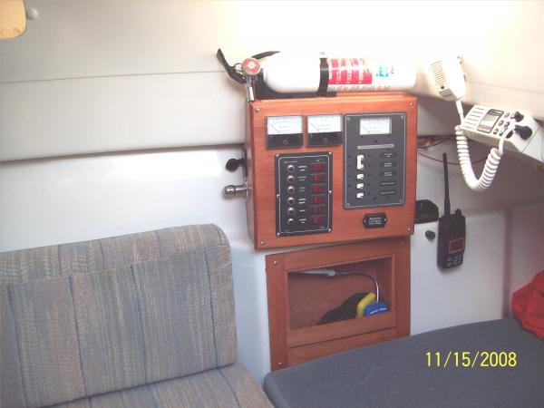 AC/DC Power Panel with DC Amp/Volt meters. Cubby hole under.  Engine hour meter on panel under AC switches.  12V outlet and cigarette light/nite lite on left side of panel. 1 of 3 fire ext.  Cabin VHF.  Hand held VHF hanging on clip.  Charger on shelf.  Note aft birth cusion is level with starboard seat.  Makes a very comfortable starboard birth.  Eliminates crawling in/out.  (The Admiral's birth.)