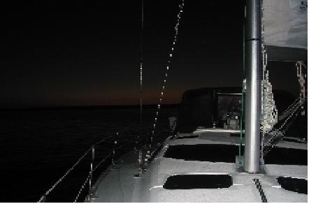 Bev at the helm at dusk in Harrington Bay