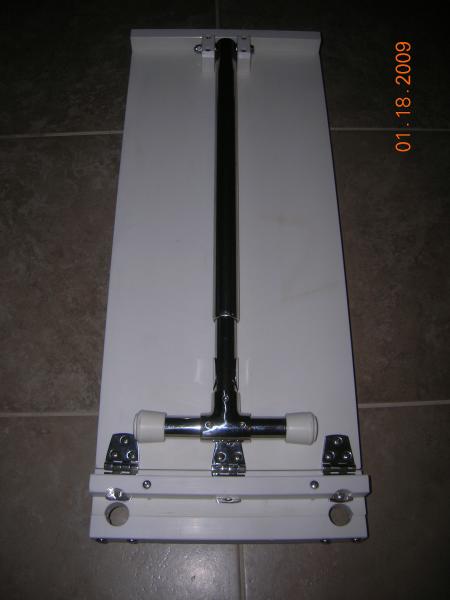 Bottom view showing the telescoping leg that locks onto the bottom of the table when in this folded position and uses a bullet latch to lock it into the extended position when in use.