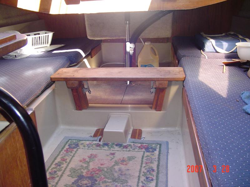 DSC00729 This is what the companionway step looks like when it's in place along the sole plate covers.  When I first bought my boat I had a heck of a time getting my cooler in the area behind this step.  I had to remove the quarter birth cushions on the left in the picture, and slide the 48 quart cooler in, behind the step each time.  Boy what a PITA that was!!!  After I modified the step, it became easy to lift my 50 qt. cooler over the mounts after removing the step.  
Last year I omitted those two quarter birth cushions in those cubby holes under the cockpit seats.  They really aren't needed and I gained more space for a second cooler and all my gear.  My cabin looks less cluttered now and I have better access to my settee compartments in there.