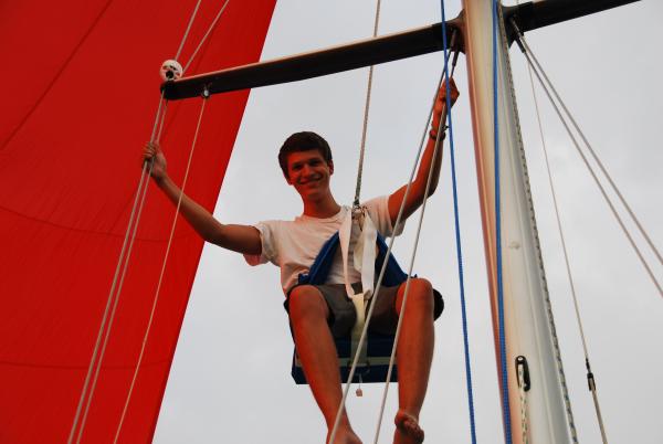 Firstborn son Will in the bosun's chair, spinnaker flying