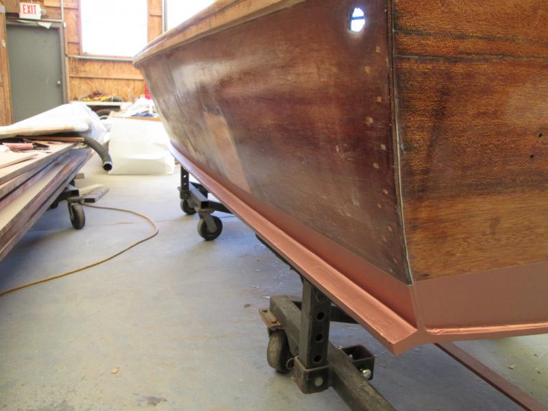 Here is the stern quarter of the little Sea Scamp 500 from 1957.  Note the bottom planking (1/2&quot; plywood) extending past the transom.  Some people wanted to plane this off, to make it 'easier' to 'glass the bottom.  I fought against this and, surprisingly, won, because I understood what it's for.  If the transom were down in the water, the boat would have to pull all that water behind it to get up and stay on plane.  But like this, once it gets going, it has to pull only 1/2&quot; of water along-- much less suction and drag, making it faster.  Consider the very excellent Dick Bertram 31' Moppies of 1960, how fuel-hungry they were, dragging a deep-V transom with over 30 degrees of deadrise.  Now look at the flat deadrise of this little skimboard of a boat, which gets up on plane with only 30-35 HP.  The down-angled chine stick helps as well.

I filled all these wood-to-wood joints with WEST epoxy, using my finger as the applicator/radius gauge.  It's sealed, strong and smooth now (note seam between transom and protruding bottom planking).  It's up to Bruce, the owner, to make sure he does the same thing inside as well.

We ended up 'glassing only the bottom, using epoxy, trimming off the edges of the 'glass at the very bottom edge of the chine stick.  The bronze bottom paint is de rigueur; non?

The hole in the hull is for the bilge pump's outlet.

25 Jul 2014