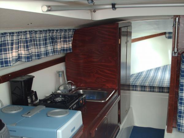 Inside Enfin! Showing the galley, storage section, 12v fridge, stove and part of the V berth