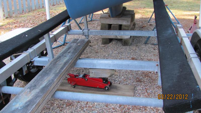 Loading her on the trailer 3 22 12 001 To slide the trailer over and inch or two one side or the other just place the jack under the center of the trailer and jack it up.  If the ground is soft or in this case has pea stones on it, just place the jack on a short plank and that trailer should slide over pretty easy on the jack's small steel wheels.  I'm using a set of blocks to pull the trailer over but you should be able to push or pull the trailer over by hand.  My trailer is 23 feet long and I'm able to push it over by hand as long as all the wheels are off the ground.  Of course, the jack needs to be place somewhere near the balancing point of the trailer.  Pretty nifty huh?