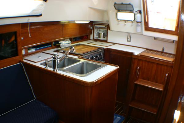 Newly furbished galley with teak veneer plywood, white Formica, built in coffee maker, new faucet and completely changed cabinet to the left of companionway stairs. We took out the small and useless drawers and replaced it with rolling double track pull out under-counter tray.