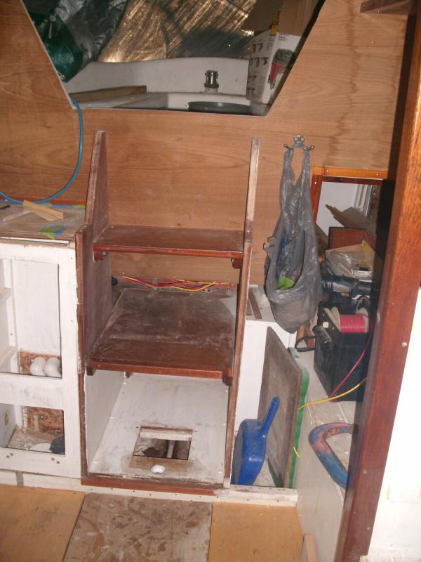 November 2011.  Aft end of cabin showing 'ladder' and cooler cubbyhole.  The access hole in the bottom of the cubby is to faciliate the cooler drain-- the white PVC receptacle leads into the bilge.

The outboard sections of sole are installed-- awaiting paint and nonskid.  The center section is just a hunk of plywood-- this will be mahogany plywood, varnished, later.