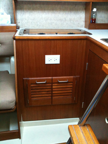 Refinished galley with GFI shore power and louvered teak doors in under stove locker.