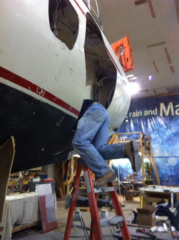 This is me operating on R33 no.15, using the hole cut by Storm Sandy (and trimmed smooth by us) to gain access to water heater, fuel tank, rudder post and steering gear, and stuffing box.  What so many owners of damaged boats don't understand is that the fiberglass repair is the EASY part!  Even a big hole is much smaller a problem than it looks to be.

For this, Jeremiah went out back to the plug, laid up a 'glass piece in this spot, and tacked it over this hole, inside which he laid up enough 'glass to be able to remove the piece and finish it from the outside.  After a new spray of Awlgrip, you'll never tell where the repair was.

Photo by Captain Mike, 22 Feb 2013