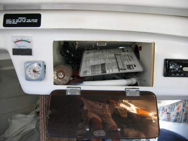 This is the cubby above the sink, with the stereo to the right.  We keep a compressed-air horn and flares there.  To the right, behind the board with the red button is the connection area for circuits.  Power comes from the switches to here to be split up for multiple loads on the same switch.  The battery gauge is to the left, above the clock.