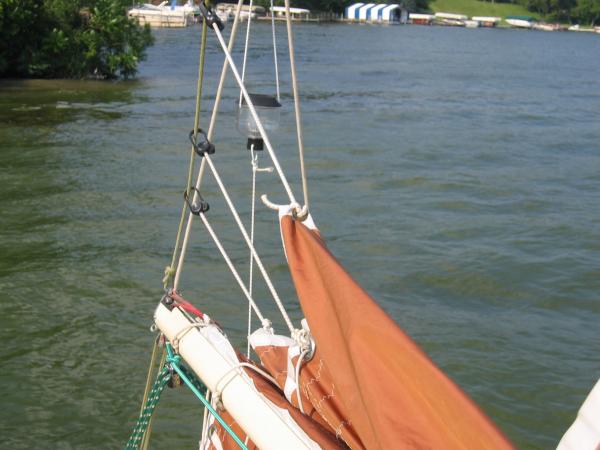 Three shock cords from the reef cringles (and one additional grommet in the leech of the main) to sliding clips on the back stay force the sail to flake itself neatly on the boom when lowered -- MUCH better than lazy jacks!