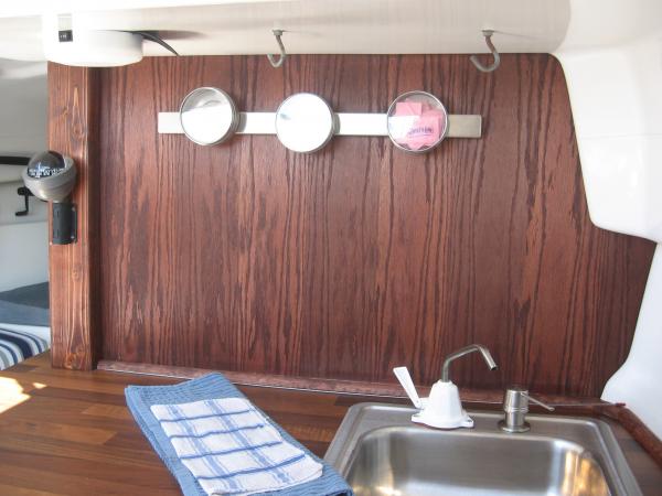 We added a counter top, installed a stainless steel sink and repositioned it to the starboard side. To make it all fit we removed and replaced the headboard with Oak veneer to replace the mirror. The circle bins are magnetic and store dry goods.